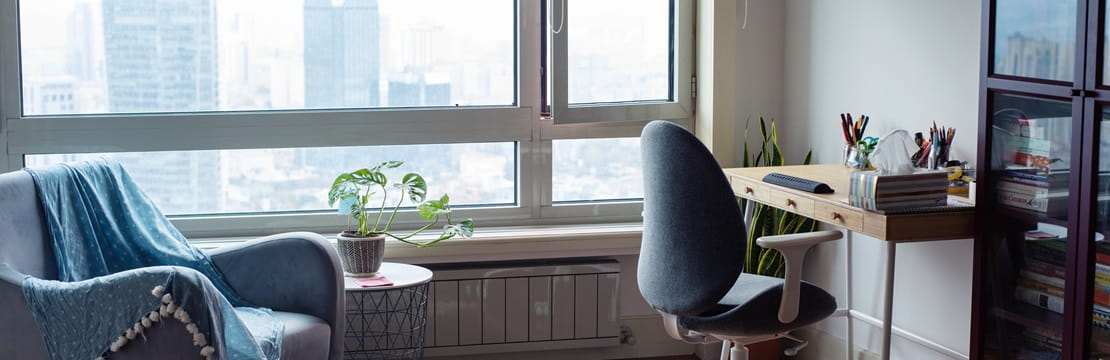 Workspace with a rolling chair and desk with a window view of a cityscape.
